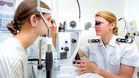 Fachärztin für Augenheilkunde während einer Behandlung mit einem Netzhaut-Laser Fachärztin für Augenheilkunde schaut durch die Optik eines Netzhaut-Laser