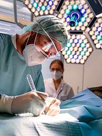 Kliniken des Bundeswehrkrankenhaus Ulm Arzt mit Maske und OP-Besteck mit Beleuchtung