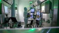 Material-Schleuse der PET-Radiopharmazie am Bundeswehrkrankenhaus Ulm Eine Person mit Vollschutz bedient ein Tastenfeld zur Bedienung der Material-Schleuse der PET-Radiopharmazie.