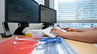 Zentrales Klinisches Management am Bundeswehrkrankenhaus Person bedient eine Computertastatur vor zwei Monitoren mit einem daneben liegendem Stetoskop