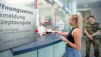 Anmeldung der Rezeptausgabe der Krankenhausapotheke am Bundeswehrkrankenhaus Ulm Eine Frau übergibt ein Rezept an der Rezeptausgabe der Krankenhausapotheke des Bundeswehrkrankenhaus Ulm