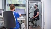 Ein Patient sitzt in einer geschlossenen Kabine während ein Lungenfunktionstest durchgeführt wird