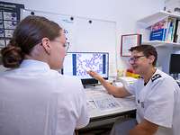 Zwei Frauen in weißer Schutzkleidung sitzen sich gegenüber