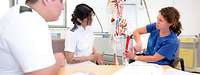 Ausbilderin mit zwei angehenden Pflegefachkräften in der Berufsfachschule für Gesundheits- und Krankenpflege