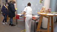 Ein Informationsstand mit einer Soldatin und zwei Zivilisten davor.