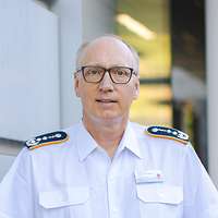 Ein Soldat in einem weißem Hemd steht vor einer Wand