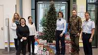 Mehrere Männer und Frauen stehen um einen Weihnachtsbaum herum