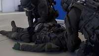 Zwei vermummte Polizisten kümmern sich um einem Übverletzten.