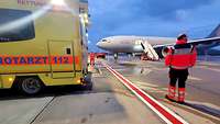 Ein Rettungswagen wartet auf das gerade gelandete Flugzeug. Dieses steht im Hintergrund