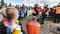Sanitäter und Feuerwehrleute transportieren einen Patienten auf einer Trage weg vom Unfallort