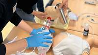 Eine Person führt eine Maskenbeatmung durch während eine andere Person einen Atemweg mittels Intubation schafft.