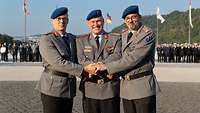 Drei Soldaten geben sich die Hände.