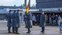 Ein Soldat gibt die deutsche Truppenfahne an den Fahnenträger zurück