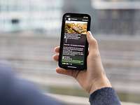Symbolbild 'Bundeswehr auf WhatsApp' Eine Person hält ein Handy in der Hand auf dem ein Kanal von der Bundeswehr zu sehen ist.