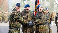 Drei Soldaten stehen zusammen und schlagen die Hände übereinander