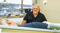 Ein Militärseelsorger sitzt am Bett eines Patienten