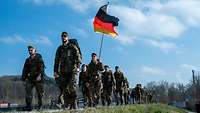 Eine Marschgruppe mit Deutschlandfahne am Donauufer