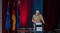 Ein Generalstabsarzt in Uniform steht an einem Pult und hält eine Rede