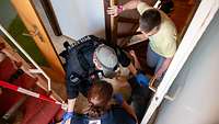 Ein Polizist Kniet in einem Treppenaufgang und versucht Erste Hilfe zu leisten zwei weiter Personen stehen neben ihm