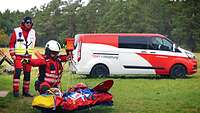 Eine Person kniet hinter der Trage an dem ein Winschseil hängt