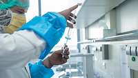 Ein Mitarbeiter führt eine Spritze in ein Gefäß