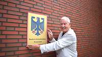 Ein Arzt hält das Schild mit dem Bundesadler und dem Titel Bundeswehrkrankenhaus Westerstede in der Hand
