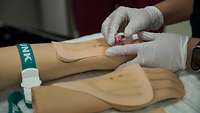 An einem Modellarm wird eine Punktion durchgeführt