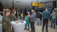 Zwei weibliche Soldaten in Uniform unterhalten sich mit Besuchenden