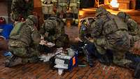 Soldaten leisten medizinische Erste Hilfe während einer Übung mit Brandsimulation im Hintergrund