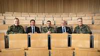 Fünf Personen sitzen nebeneinander in einem Hörsaal