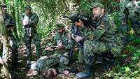 Soldaten versorgen eine Verletzte Person in einem Wald
