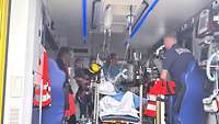 Zwei Sanitäter erklären die Ausrüstung eines Krankenwagens einer Gruppe.