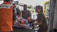Soldaten lagern einen Verwundeten auf einer Trage auf eine Andere